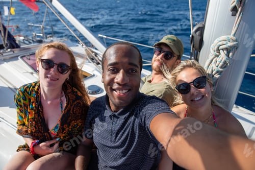 Preview: Multiethnic group of smiling people in a boat taking a selfie. Leisure and carefree concept