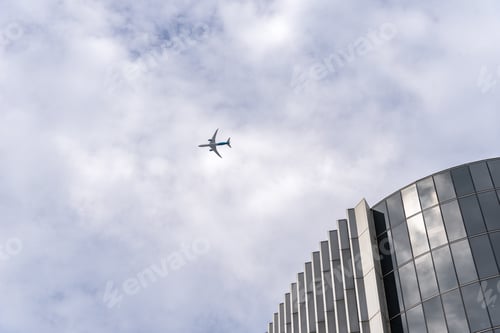Preview: Plane over skyscrapers in the city of London. Low angle view against cloudy sky