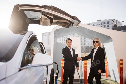 Preview: Woman shaking hands with seller while buying electric car