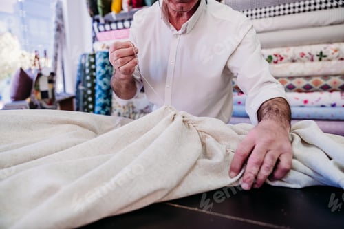 Preview: senior man working in atelier cutting curtains. Small business