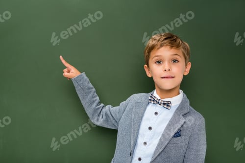 Preview: schoolboy pointing at copy space next to chalkboard