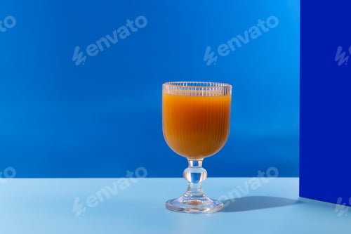 Preview: A glass of refreshing orange juice with a blue tint is placed on a table