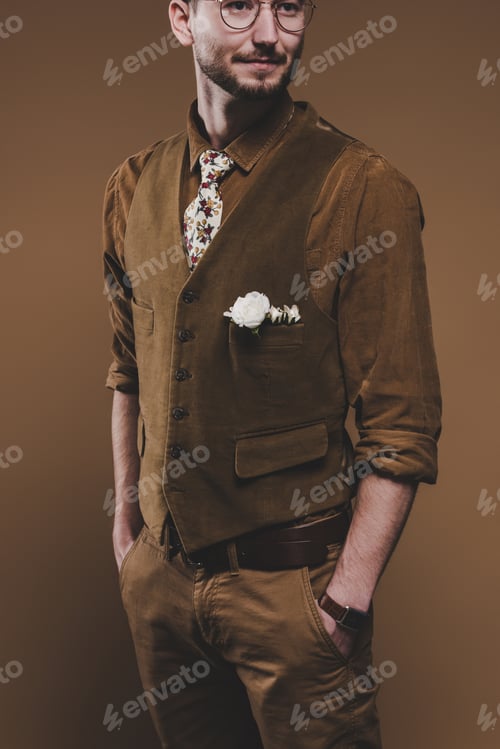 Preview: Young man in vintage styled clothes with boutonniere isolated on brown