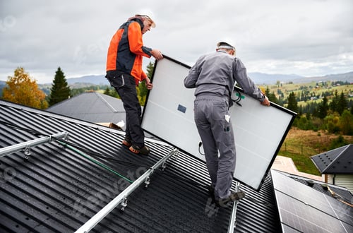 Preview: Technicians carrying photovoltaic solar module while installing solar panel system on roof of house