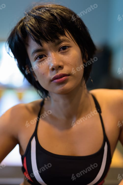 Preview: Face of young beautiful Asian woman working out at the gym