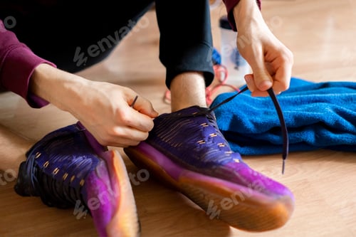 Preview: athlete tie shoelaces in the gym on the wooden floor