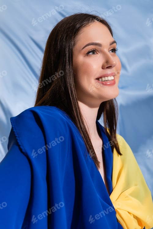Preview: pleased ukrainian woman in color block clothing posing near blue fabric