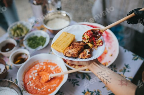 Preview: Tattooed chef adding vegetables to the plate of Mexican chicken, crispy Polenta, bowls of dressings