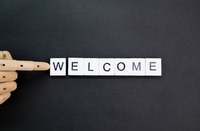 Preview: Welcome Message with Wooden Hand on Black Surface