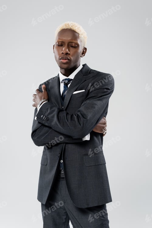 Preview: stylish african american businessman in suit posing with crossed arms isolated on grey