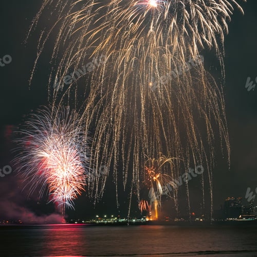 Preview: Vibrant display of fireworks bursting in the night sky above a tranquil body of water
