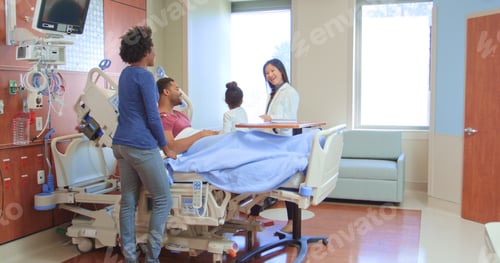 Preview: Female Doctor Wearing White Coat Meeting Family Visiting Father In Hospital Bed