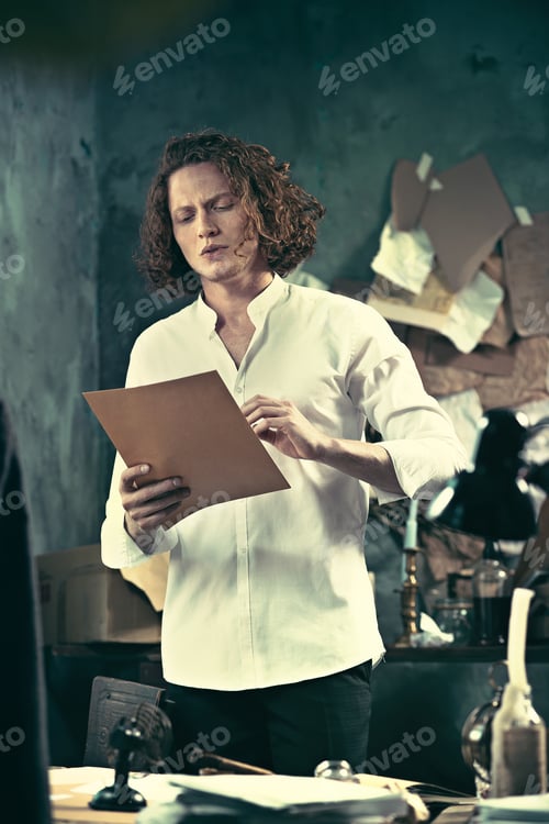 Preview: Writer At Work. Handsome Young Writer Standing Near The Table And Making Up Something In His Mind