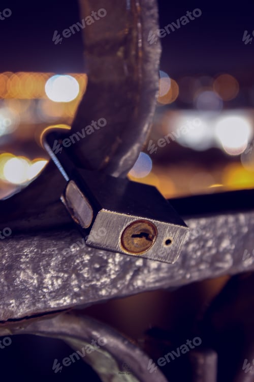 Preview: Closeup of a silver padlock securely fastened to a bridge