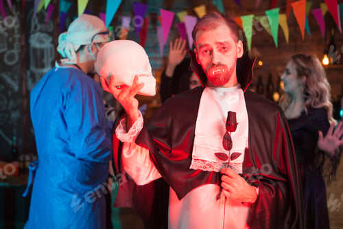 Preview: Count dracula holding a human skull and looking into the camera at halloween celebration