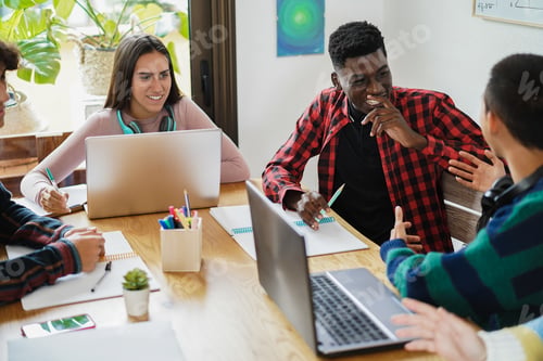 Preview: Multiracial students reading books and using laptop computers while studying at school