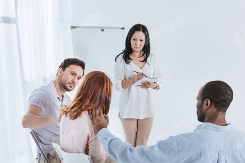 Preview: psychotherapist taking notes while anonymous group supporting depressed woman