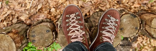 Preview: Top view man standing with hiking mountain boots on autumn leaves and wood background
