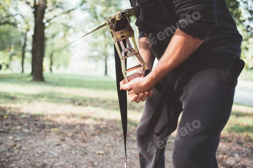Preview: Close up man hand preparing the equipment fixing rope tree slacklining