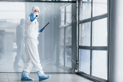 Preview: Worker in Protective Suit Walking Through Building