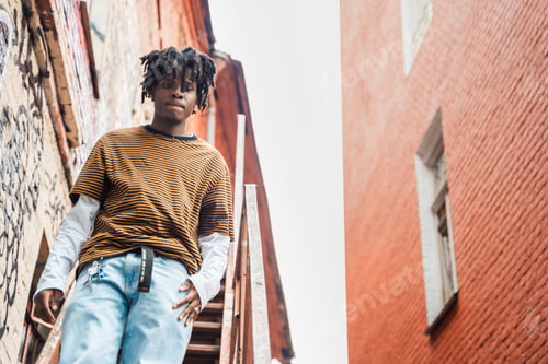 Preview: Portrait of young handsome stylish black man with natural hair dreadlocks. Afroamerican guy. Stairs,