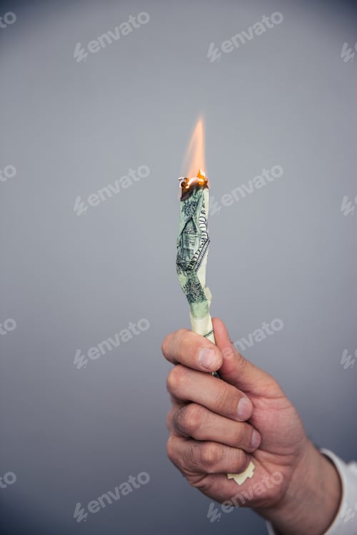 Preview: Male hand holding a burning US dollar bill
