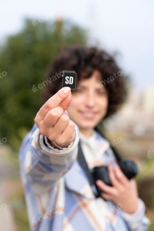 Preview: Curly hair woman showing an sd memory card to the camera