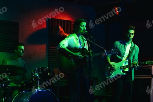 Preview: Musicians In Stage With Colorful Lights Performing In A Live Concert