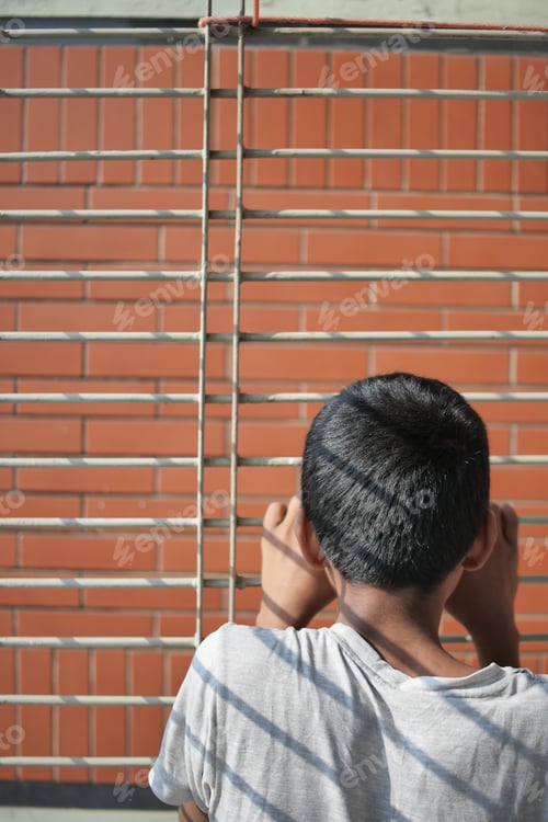 Preview: sad teenage boy looking through window