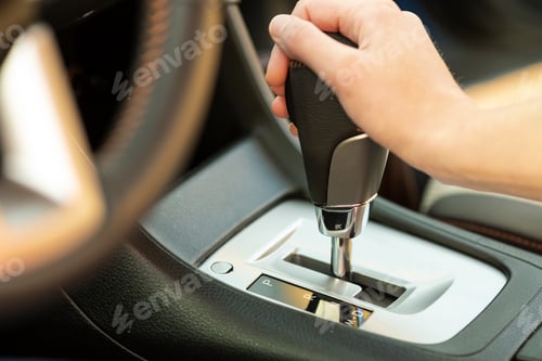 Preview: Close up of woman driver holding her hand on automatic gear shift stick driving as car.