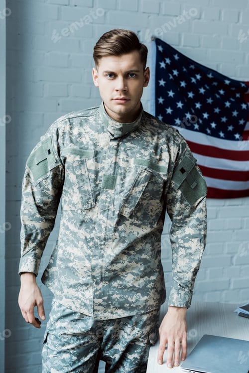 Preview: handsome man in military uniform standing near table in office