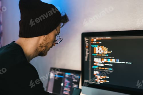Preview: Young man mobile developer writes program code on a computer, programmer work in home office.