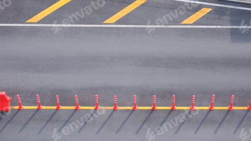 Preview: Row of orange plastic traffic posts demarcate traffic lane on street in car parking, view from above