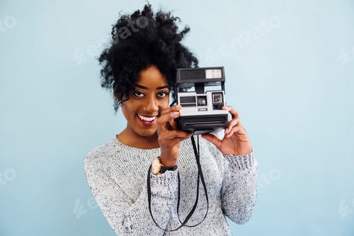 Preview: Woman with instant camera looking at camera smiling