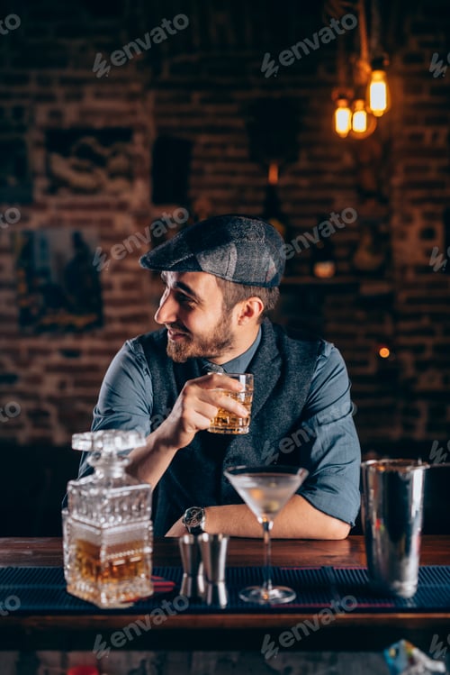 Preview: Cheerful bartender enjoying an alcoholic drink at pub, bar or restaurant. Evening relaxation concept
