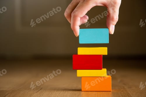 Preview: Businesswoman building a tall tower with colorful wooden blocks