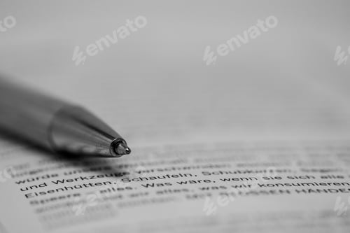 Preview: Greyscale closeup shot of a pen on a printed paper with writing in German