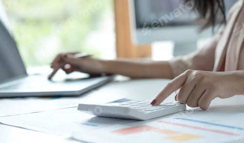 Preview: Close up young woman using calculator and laptop, checking domestic bills, sitting at table with