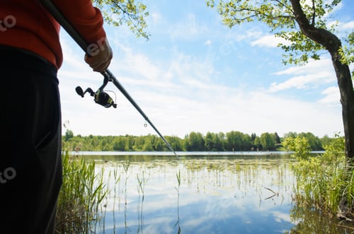 Preview: Fishing on the lake. Fisherman holding a fishing rod outdoors close-up. Fishing on a wild lake