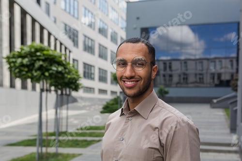 Preview: Close-up photo portrait of young entrepreneur wearing glasses, hispanic man smiling and looking at