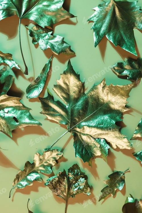 Preview: Vertical image of metallic gold autumn leaves lying on orange background