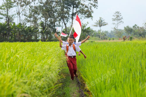 Preview: Elementary Student In Uniform Holding Indonesian Flags Celebrating Patriotism In Nature