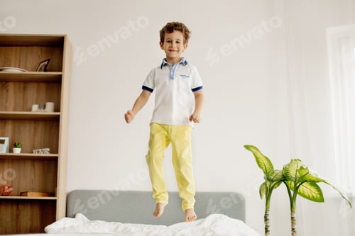 Preview: A little boy jumps on his bed in the bedroom and laughs.