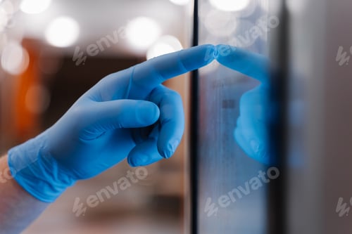 Preview: Cropped shot of mans hand in latex medical glove, uses touchscreen