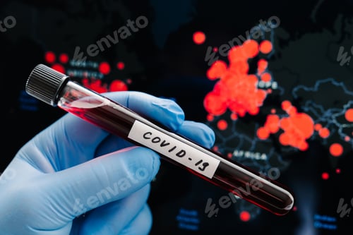 Preview: Hand in rubber medical gloves holds test tube containing patients sample against map of covid-19