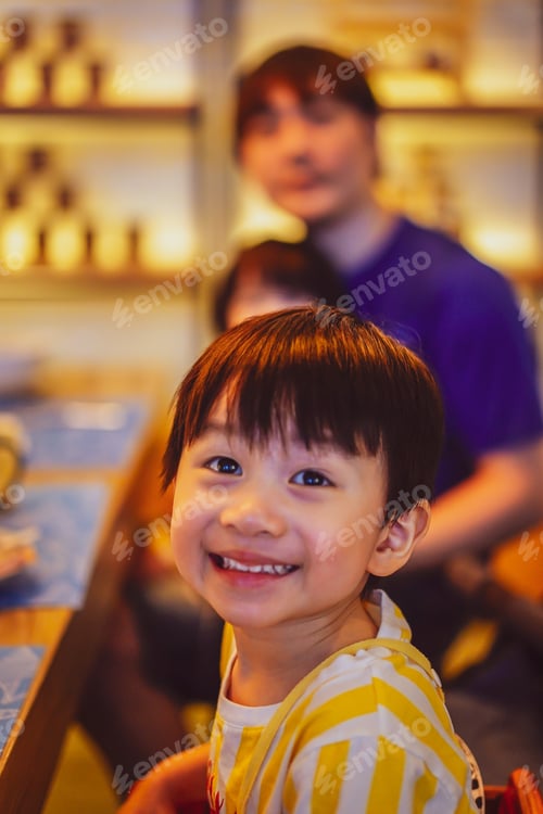 Preview: A boy sitting with smiling face in the restaurant.