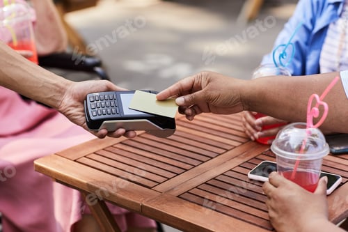 Preview: Close up of senior woman paying to waiter in outdoor cafe