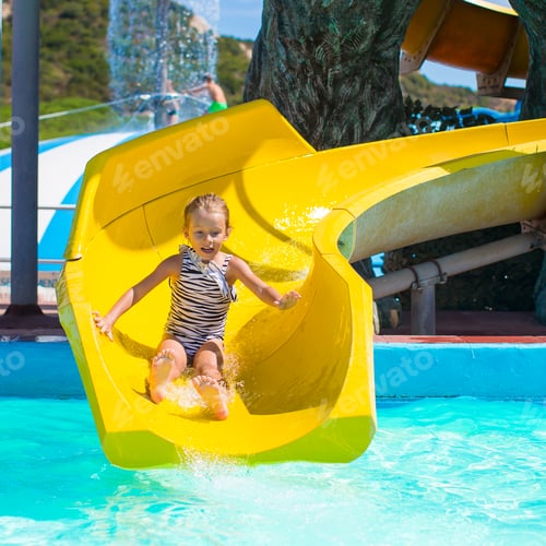 Preview: Little girl on water slide at aquapark during summer holiday