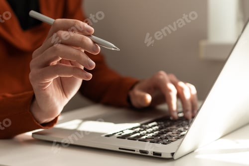 Preview: Meeting report in progress. Business man with pen in hand typing on laptop computer keyboard on desk