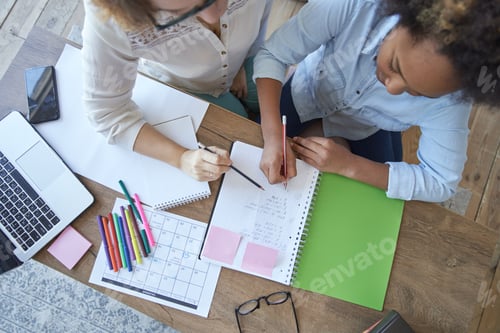 Preview: Top view of mixed race teen girl doing math task, school homework together with female teacher in
